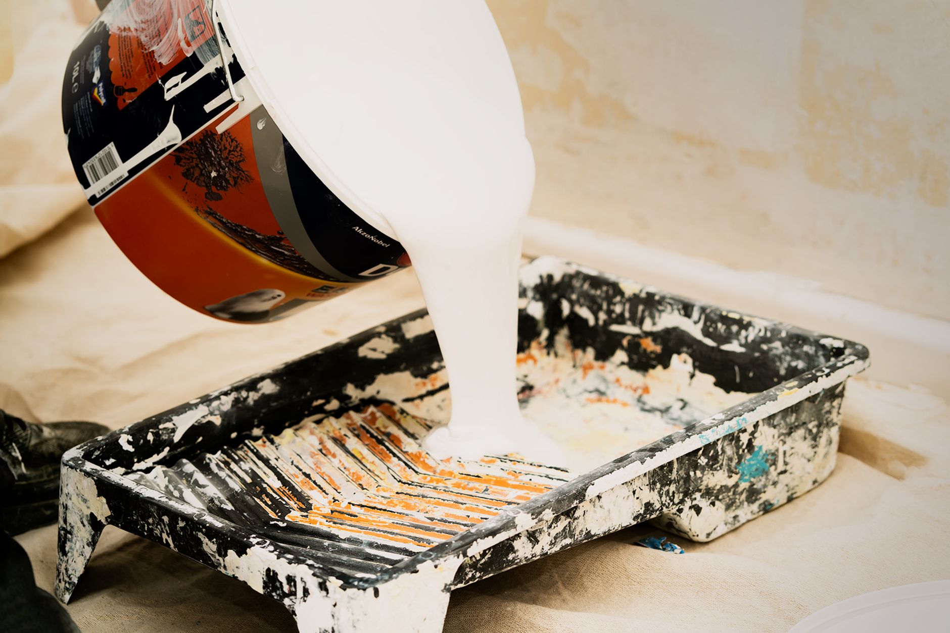 White paint being poured into a tray for home renovation, showcasing the preparation for a painting project in Long Beach, CA